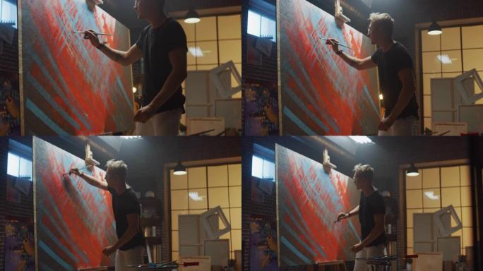 才华横溢的男性艺术家用画笔猛烈地绘画，他创作了现代油画杰作。创意工作室，带有醒目颜色的大画布。拍摄后