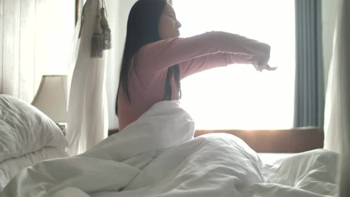 年轻的亚洲白人妇女在清晨醒来，然后躺着伸展。在家。室内