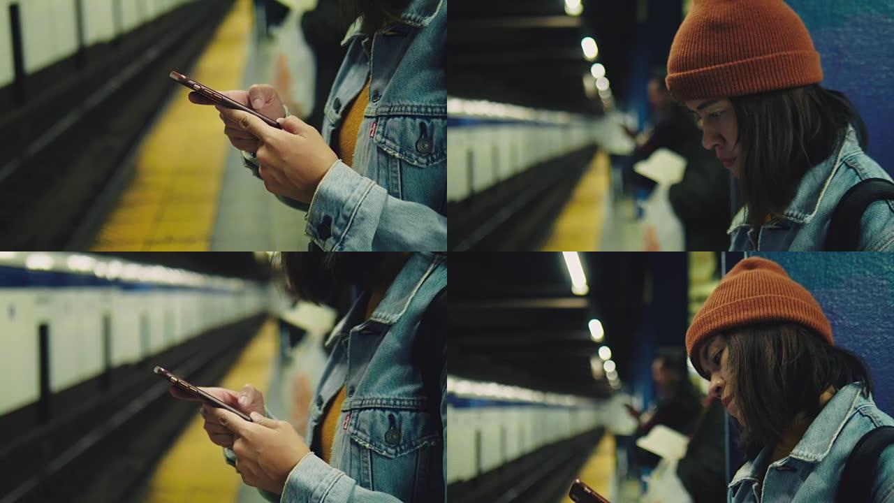 年轻的亚洲妇女在地铁站台上等着手机发短信。