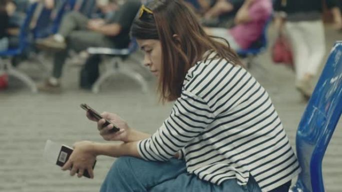 时髦的女人在机场候机室等候登机时使用智能手机。