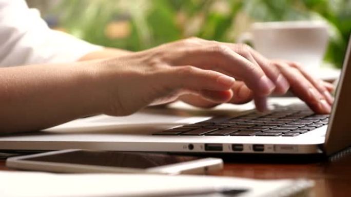 女性手指按下按钮并在笔记本电脑上打字的滑动镜头。在家网上工作的女人。UHD