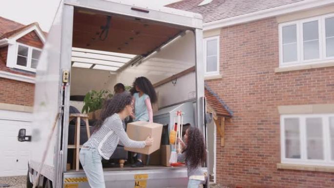 一家人站在搬家卡车的后面，将箱子装进新家，以慢动作拍摄。