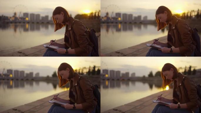 十几岁的女孩坐在路堤上，在日落时素描