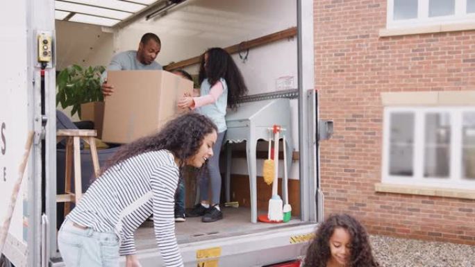 一家人站在搬家卡车的后面，将箱子装进新家，以慢动作拍摄。