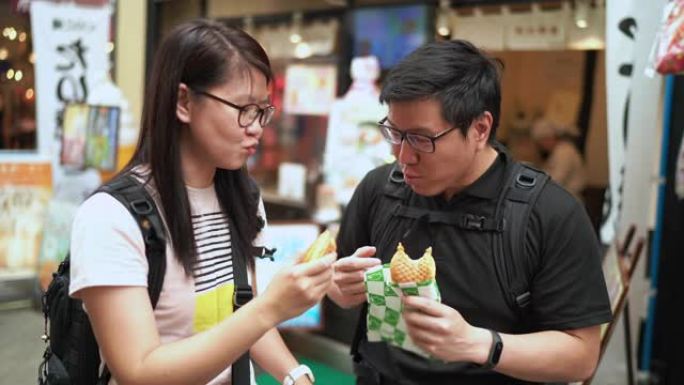 朋友旅游在东京街头食品市场吃羊角面包Taiyaki (日本鱼形蛋糕)