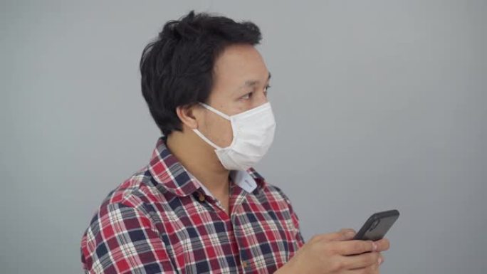 亚洲男子戴口罩使用智能手机肖像