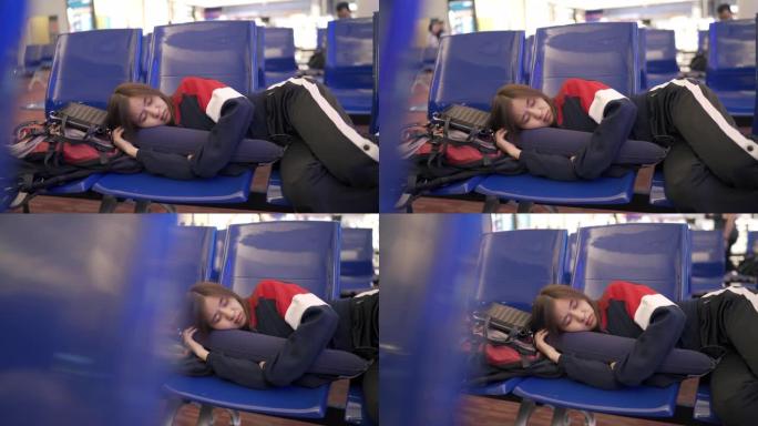 在机场航站楼，运输站和旅客旅行等待航班时，亚洲妇女用枕头睡觉的平移场景