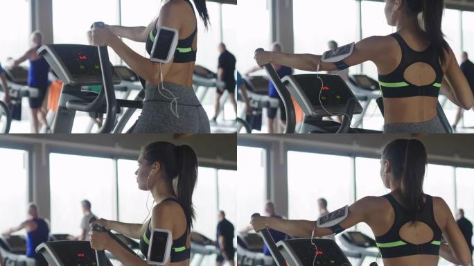 一个美丽的健康女孩，微笑着用智能手机听音乐，同时使用健身器材锻炼身体。