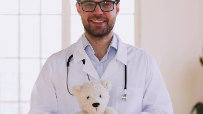 合格的男医生儿科医生抱着泰迪熊看着相机