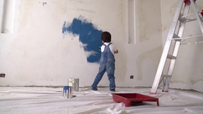 可爱的小男孩在家里用油漆滚筒绘画的DIY项目中帮忙