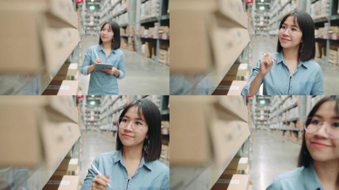 年轻的亚洲老板商人或工人在仓库里用数字平板电脑计算库存。女性企业家在仓库里计算库存。