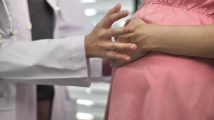 医生在医生办公室触摸孕妇的手