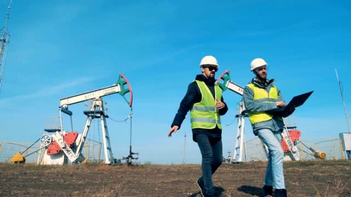 男性能量学工作者正在远离油泵，油架。石油工业，石油工业，石油部门概念。