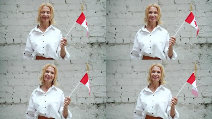 成熟的加拿大妇女在砖墙背景上举着加拿大国旗