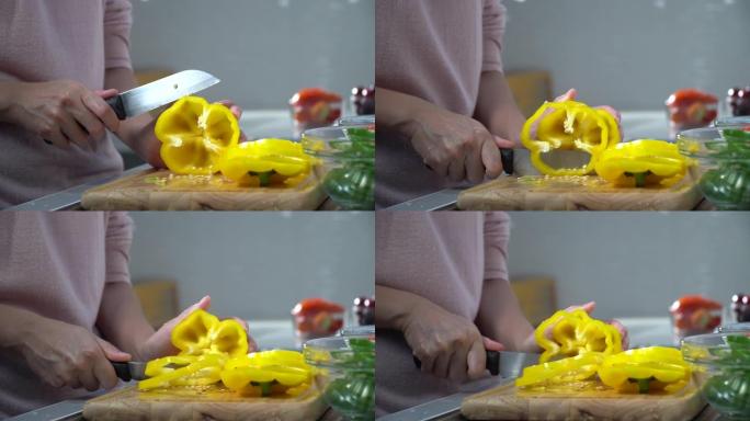 女厨师的手在木制砧板上切黄辣椒