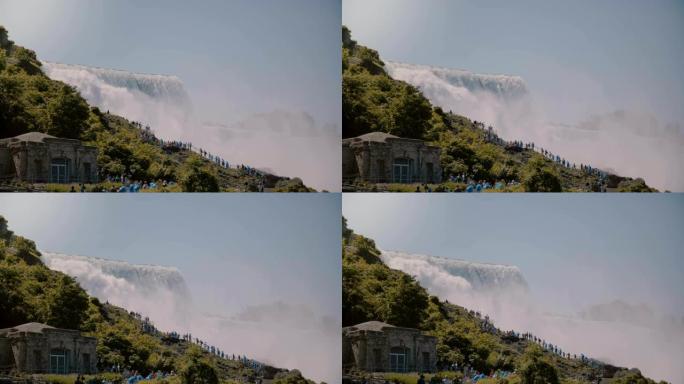 阳光明媚的日子，穿着雨衣的游客在史诗般的美丽的尼亚加拉大瀑布瀑布上走上梯子的电影视点镜头