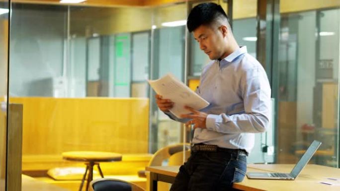 年轻的亚洲商人在办公室阅读商业报告