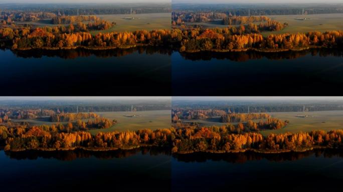 无人机飞越令人难以置信的静止湖，朝着白俄罗斯覆盖着薄雾的黄色秋天森林树木。