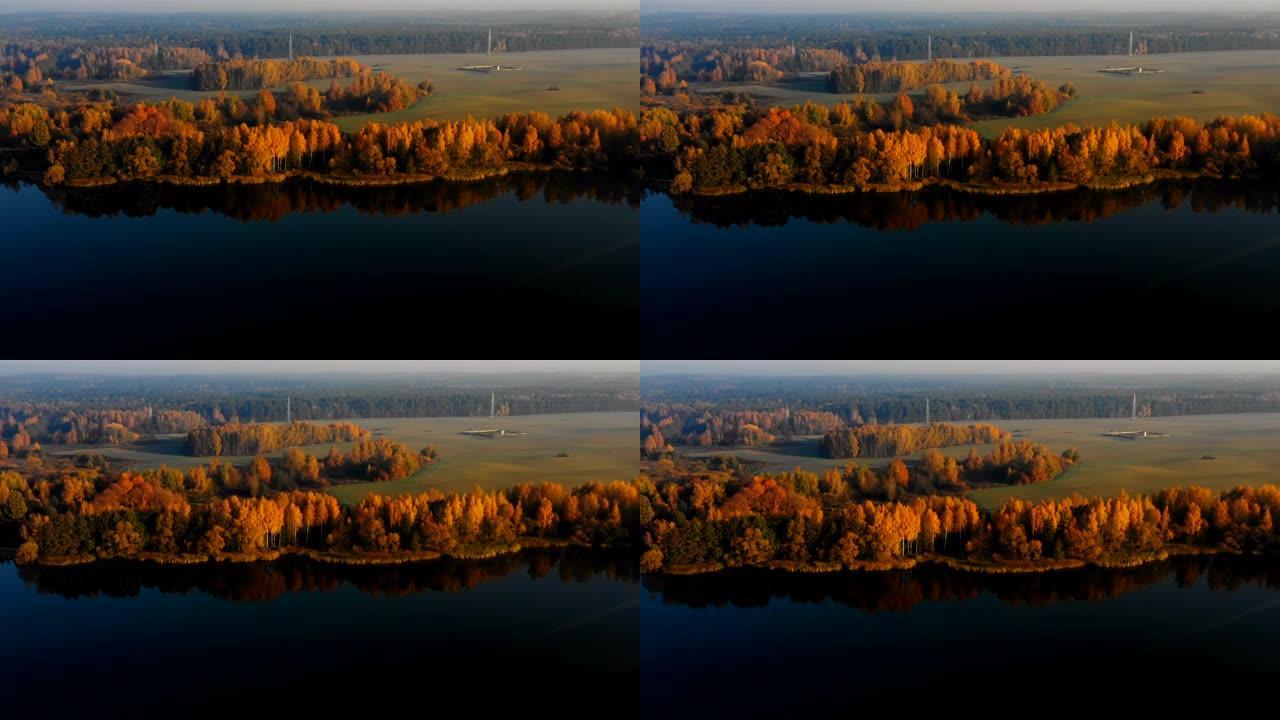 无人机飞越令人难以置信的静止湖，朝着白俄罗斯覆盖着薄雾的黄色秋天森林树木。
