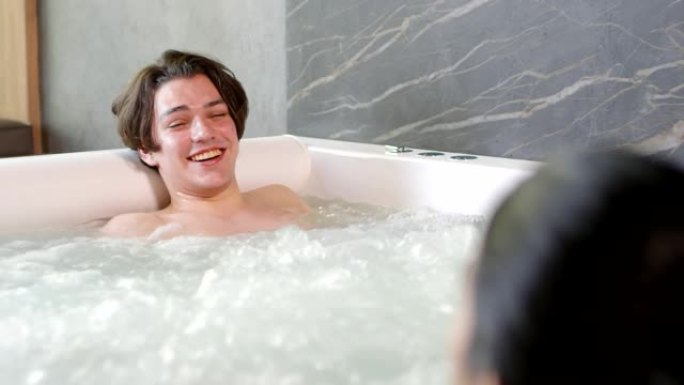 年轻的白人男子在热水浴缸里大笑