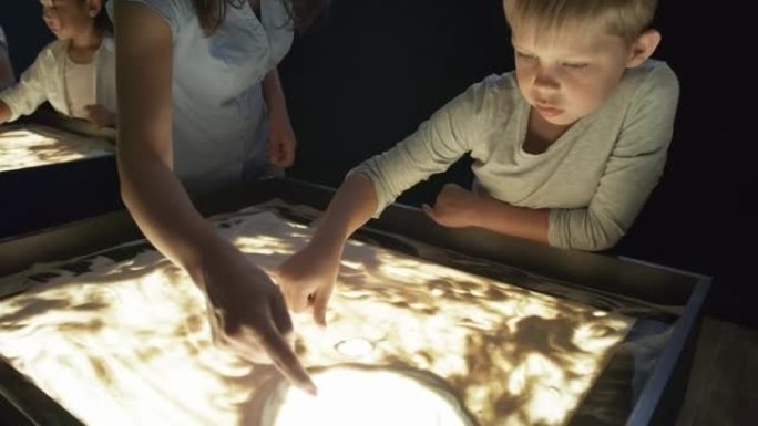 美术老师为用沙子绘画的男孩提供建议