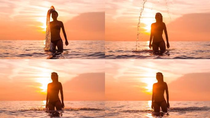 热带度假的女人在日落时将长长的湿头发向后扔在海里，水滴掉下来