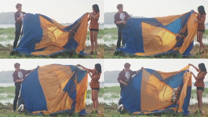 年轻的亚洲露营者夫妇在海边附近的户外帐篷露营装备。