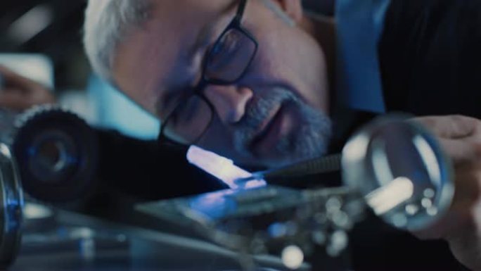 聚焦中年工程师的特写肖像，在眼镜中使用高精度激光设备，使用透镜和光学器件进行精密电子设备。测试超导体