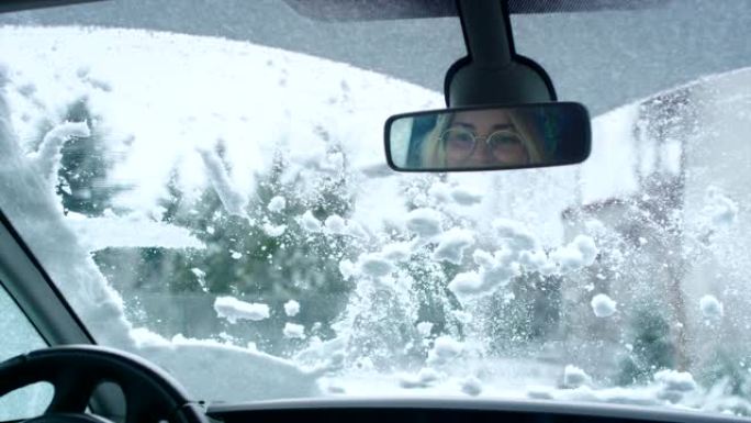 司机的视点。汽车刮水器清洁窗户上的雪