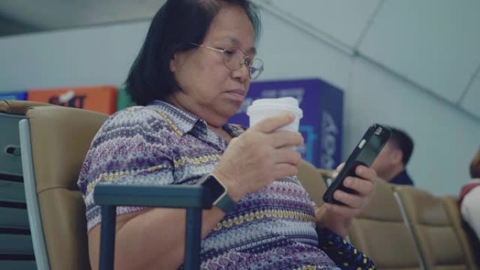 亚洲资深女性在机场使用智能手机
