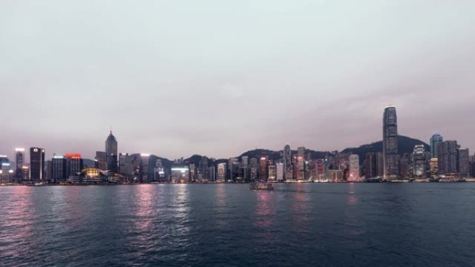 从白天到晚上，T/L是香港的城市景观和黄昏的垃圾船