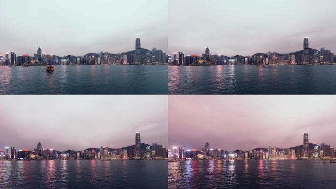 从白天到晚上，T/L是香港的城市景观和黄昏的垃圾船