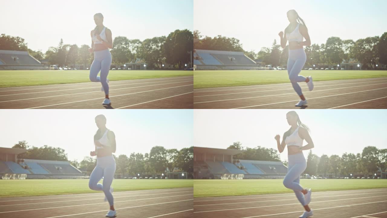穿着浅蓝色运动上衣和打底裤的美丽健身女孩在体育场慢跑。她在一个温暖的夏日下午跑步。运动员在赛道上进行