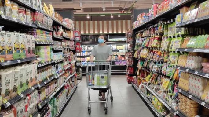 一位亚洲华人女性戴着口罩去超市买菜
