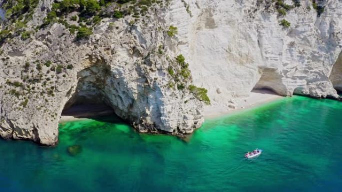意大利加尔加诺国家公园沿雄伟的白色悬崖在阳光明媚的绿松石海上的WS鸟瞰船