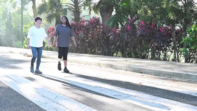 一名亚洲印度残障人士假肢运动女子在公园晨间与一名活跃的中国高级女子慢跑