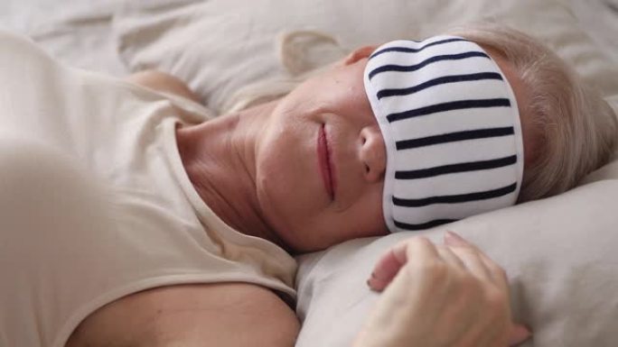 安详健康的老妇人戴着睡眠面具睡在床上