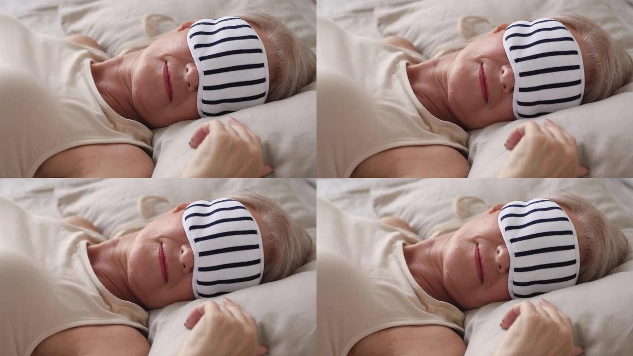 安详健康的老妇人戴着睡眠面具睡在床上