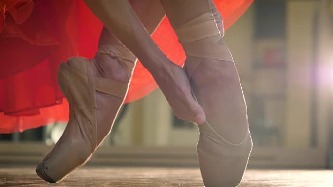 灵活的芭蕾舞演员1英尺，在木地板上穿着红色连衣裙，棕色芭蕾舞鞋跳舞。