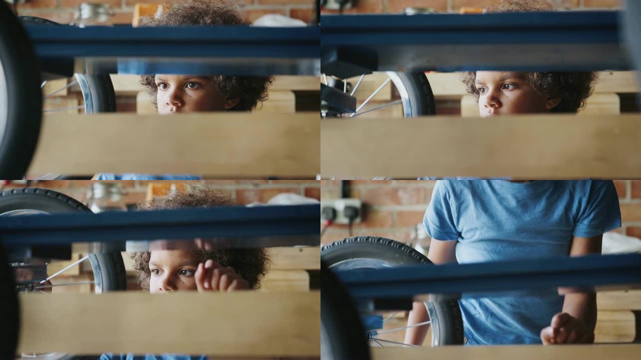 十几岁的混血男孩在车库里检查他的赛车卡丁车的特写镜头，通过卡丁车框架看到，选择性聚焦