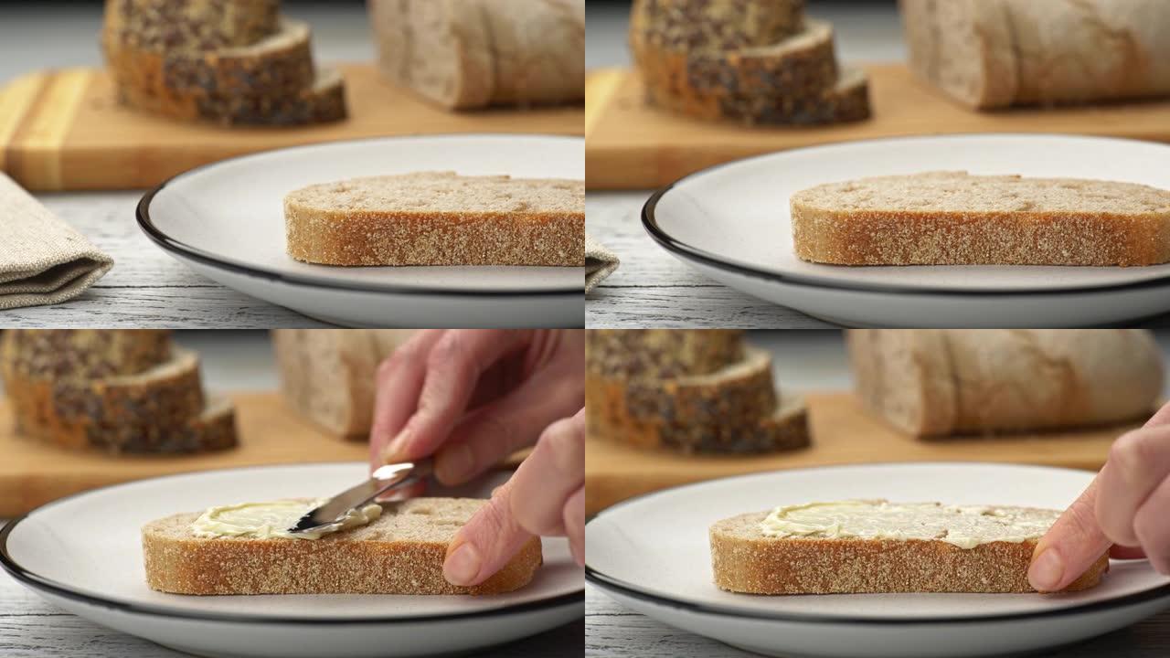 女性手在面包上涂抹黄油。黄油面包。背景UHD切片面包，4K