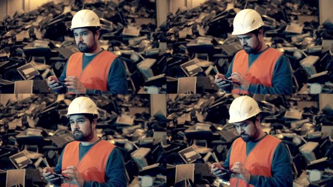男工人正在室内垃圾场操作智能手机