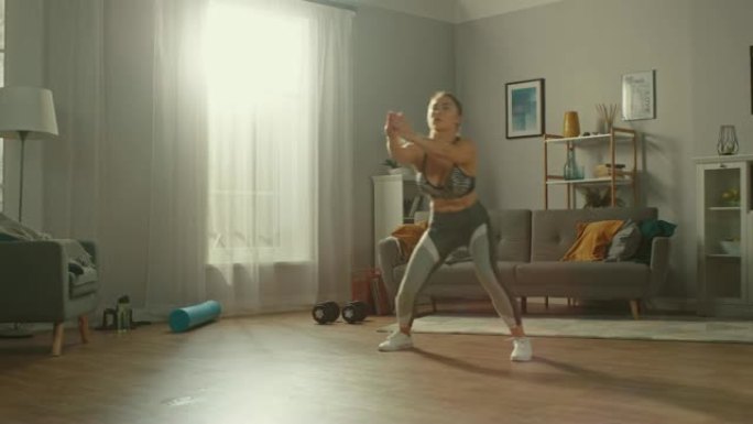 穿着运动服的强壮而美丽的运动健身女孩正在她阳光宽敞的起居室里做有氧运动，室内简约。