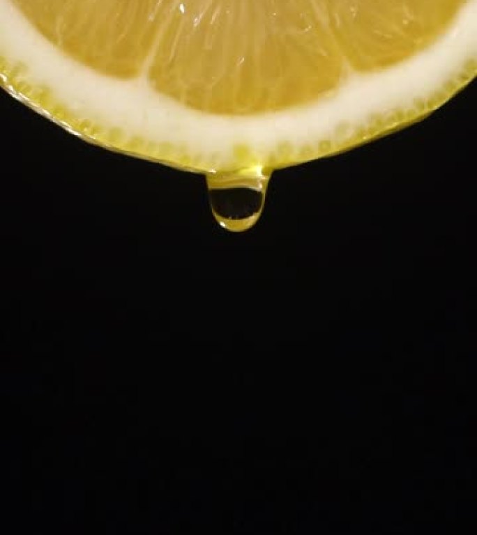 垂直和慢动作: 柠檬片上的一滴液体在黑色上