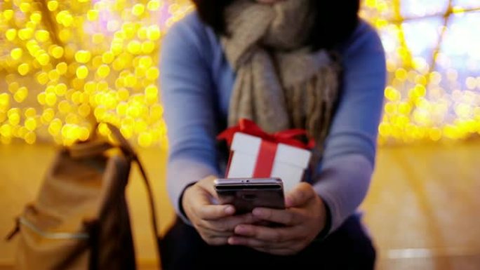 女人用手机和礼品盒庆祝圣诞节和新年，慢动作