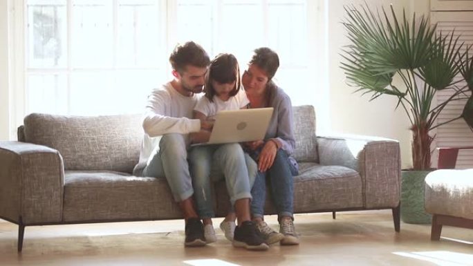 快乐的父母和小女儿在客厅使用笔记本电脑