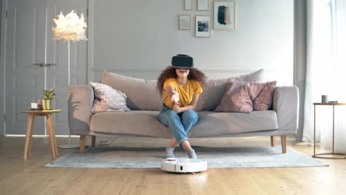 智能家居概念。机器人胡佛正在和一个戴着VR眼镜的女人打扫公寓