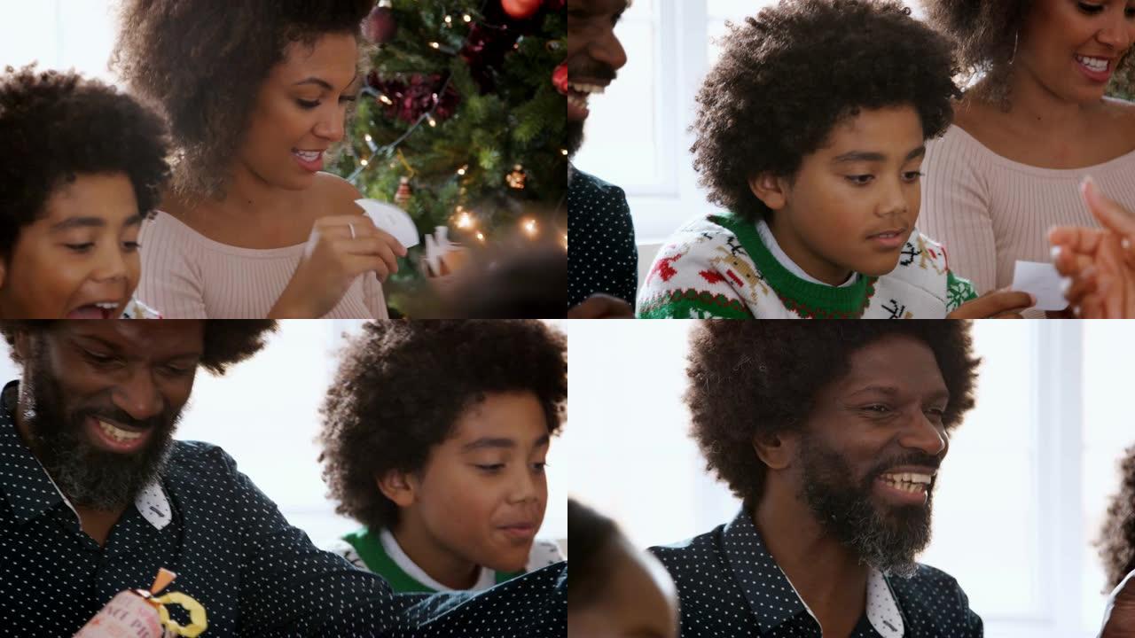 圣诞节那天坐在餐桌上的多民族家庭的平移镜头从他们拉出来的圣诞饼干中拿笑话，特写镜头