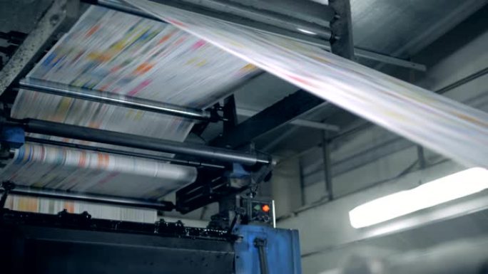彩色纸页正在印刷印刷机中移动。印刷报纸。
