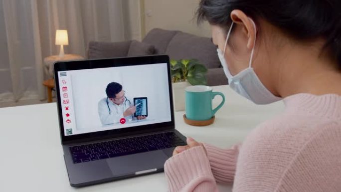 亚洲女性在家与亚洲医生视频通话的后视图。病人女孩通过视频会议听医生的肺部x光结果。冠状病毒，检疫和自
